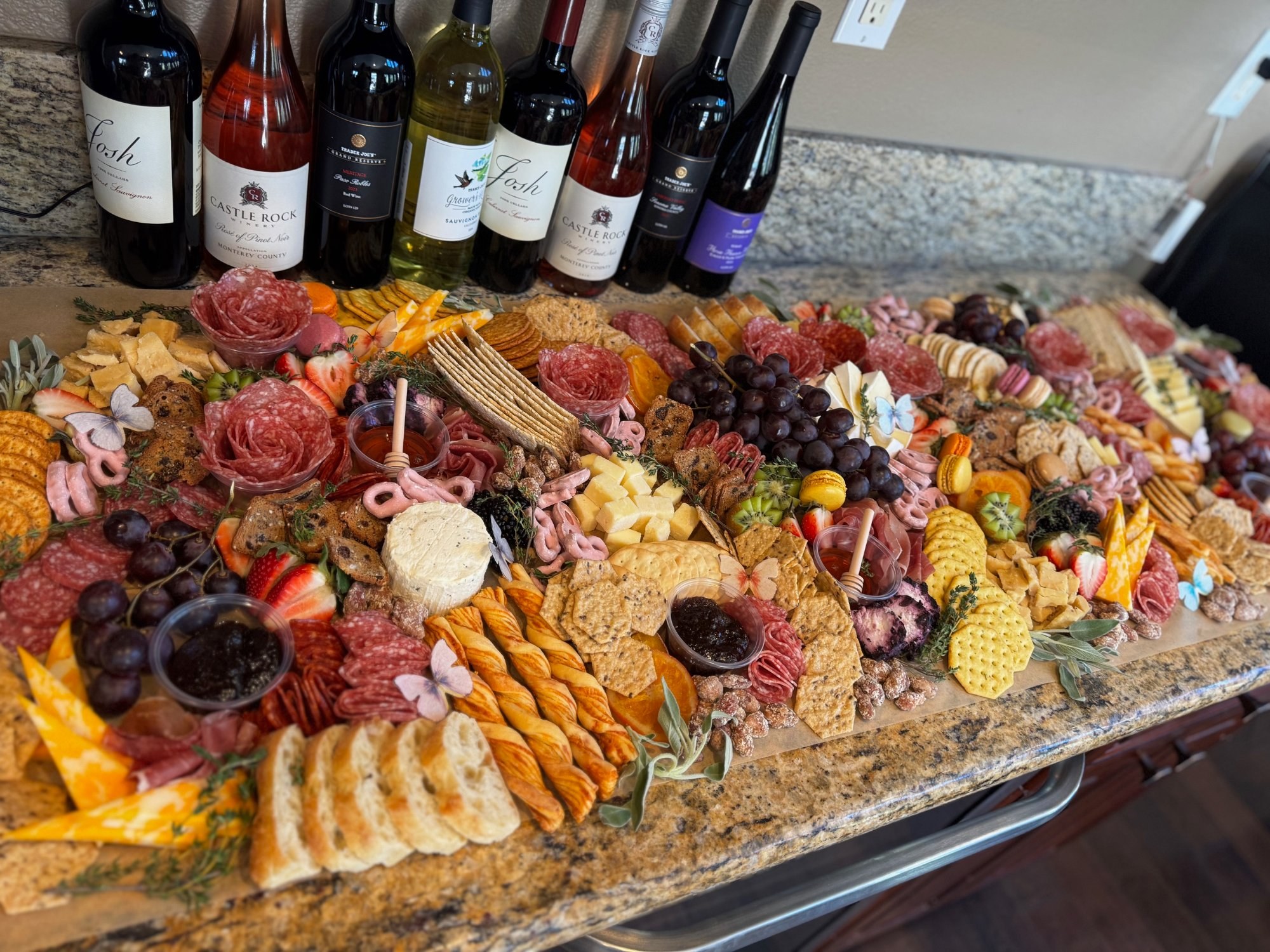 Full charcuterie board with wine bottles by Vineyard Valley Charcuterie